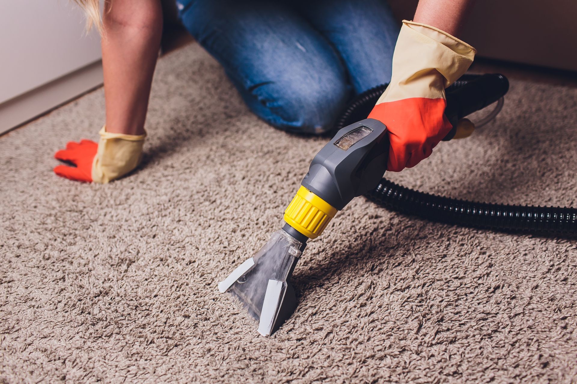 Woman removing dirt from carpet with vacuum cleaner in room.